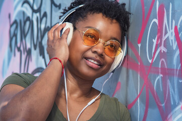 young woman with headphones on graffiti wall