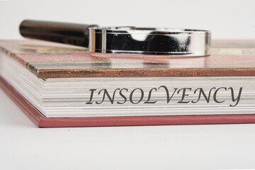 Debt relief concept. A word INSOLVENCY on a book with a magnifying glass on top on a white background - obrazy, fototapety, plakaty