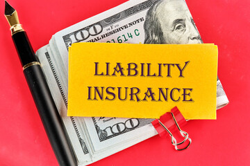 Text Liability Insurance on a sticker lying on dollar bills on a red background, next to a fountain pen - obrazy, fototapety, plakaty