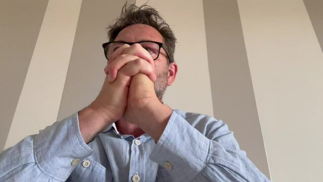 One man working on laptop with stress and anxiety alone. Camera webcamera view. Professional freeance with glasses using computer keyboard pov view. Doubts and frustration concept business lifestyle