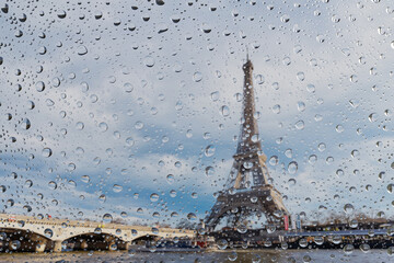 View on Paris city through water drops on glass after rain. Weather and forecast concept.