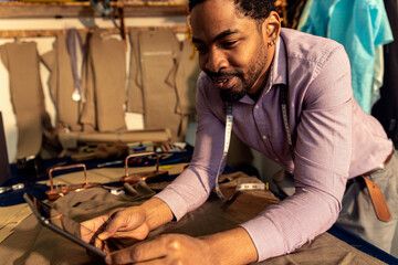 Male fashion tailor using tablet in his workshop.