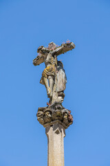 Fototapeta na wymiar A close-up of a weathered Jesus Christ statue on a cross with intricate details and sky in the background, capturing the essence of faith and history
