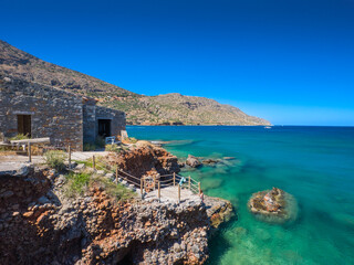 Buildings on small cliff on the seafront (Plaka, Crete, Greece) - obrazy, fototapety, plakaty