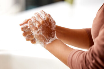 Soap, foam and person washing hands in home, kitchen or bathroom for protection from bacteria...