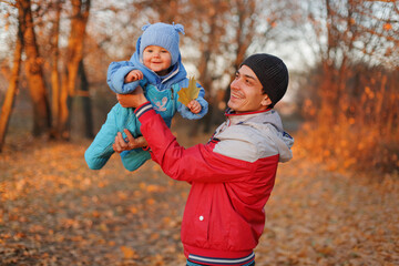 Overjoyed baby girl flying in father hands while having fun in autumn park man raising his arms holding infant daughter enjoying fall walking