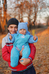 Happy father's day. Smiling handsome man holding baby daughter while standing in autumn park playing in open air enjoying warm days and joyous family walking