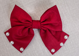 Red hair bow on textured surface with copy space - obrazy, fototapety, plakaty