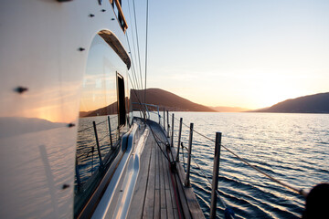 Yacht sailing at sea at sunset. Traveling with amazing view and gorgeous landscape, beautiful nature, mountains, coast. Summer vacation, adventure. Tourism on sailboat. Sustainable, ecological travel