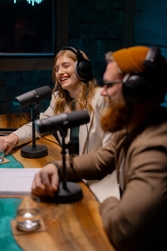 Man and woman are sitting in front of microphones in a studio. Podcast studio concept