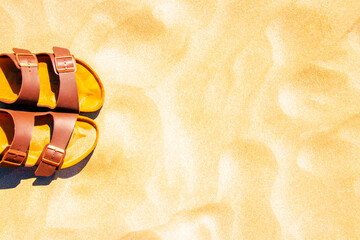 Summer vacation background. Brown shoes or sandals on a golden sunny sandy beach. Advertisment...