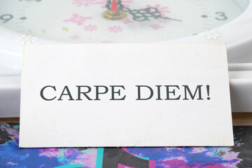 The Latin phrase Carpe Diem, a quote from Horace, means seize the moment. Live in the present written on a white business card
