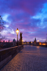 Charles Bridge at dawn, silhouette of figures of saint sculptures red dramatic sky