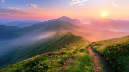 Beautiful colorful sunrise in mountains with green grass and path on mountain slope in misty valley