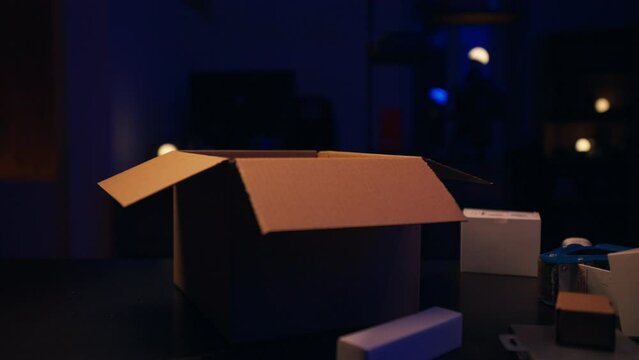 A Person Is Opening A Cardboard Box In A Dark Room