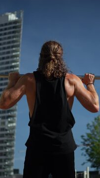 Man performing pull-Ups in the street. Guy working out on pull-up bars