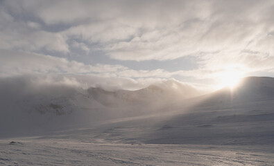 A low sunbeam shines through a col in the Sylarna mountains on a ski tour in Sweden