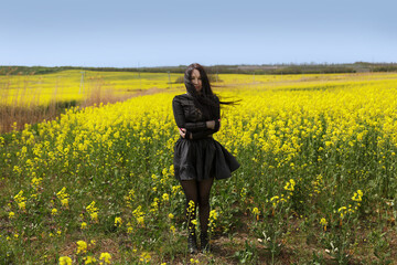 Portrait of a girl in a meadow of rapeseed flowers. Beautiful Woman with emotions of freedom.