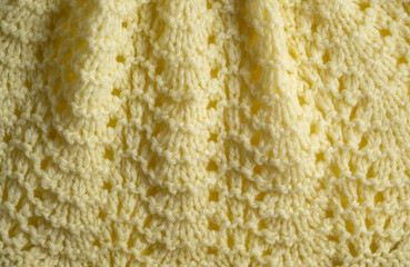 Fragment of hand knitted fabric light yellow. beautiful pattern