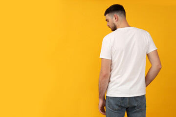 A young guy in a white t-shirt on a yellow background