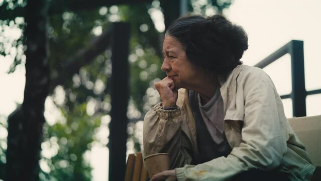 Lonely female beggar crying in park sitting alone on bench, poor lady needs help