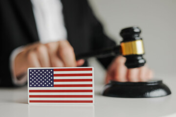 Judge's hand holding wooden gavel. Flag of USA. Concept of USA justice system
