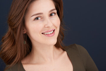 A close-up portrait of a beautiful young woman with pearly white teeth and green eyes