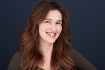 A close-up portrait of a beautiful young woman with pearly white teeth and green eyes looking directly into the camera with a lovely smile