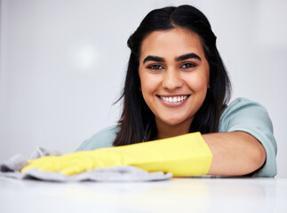Indian woman, portrait or cleaner with spray bottle for table, kitchen counter or dirty furniture in home. Smile, maid or janitor washing messy surface with product, liquid soap or cloth with gloves