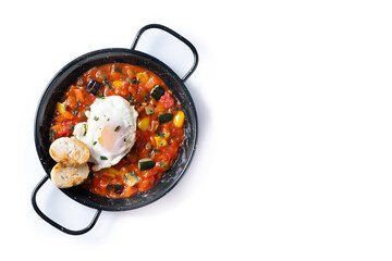 Vegetable pisto manchego with tomatoes, zucchini, peppers, onions,eggplant and egg, served in frying pan isolated on white background. Top view. Copy space