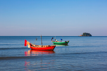 Two small fishing boats rest on the calm sea in the morning light in the eastern Gulf of Thailand.