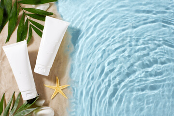 Top view of unbranded sunscreen tubes on a sandy surface with tropical leaves and pool water, ideal for summer health and skincare adverts or text
