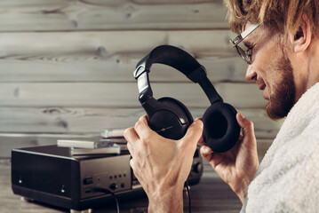 Happy man with headphones and old tape recorder resting at home while play nostalgic music. Retro...