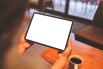 Mockup image of a woman holding digital tablet with blank white desktop screen in cafe - 792602133