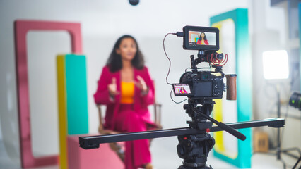 Vibrant Video Production Scene With A Black Female Host In A Pink Suit Engaging In A Lively...