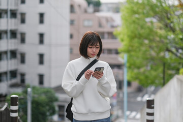 Fototapeta premium 坂の上でスマートフォンを見る女性