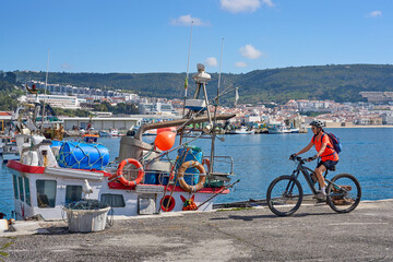 nice senior woman cycling with her electric mountain bike on the fishermens jetty of Sesimbra,...
