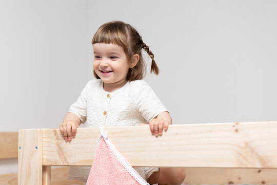 Smiling Toddler Girl Leaning on Wooden Furniture