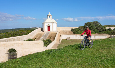 woman with electric mountain bike at Santuário de Nossa Senhora do Cabo Espichel, a famous pilgrims church at Cabo Espichel near Sesimbra, Portugal