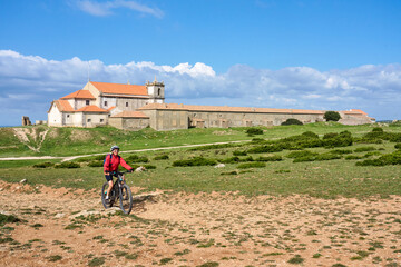 woman with electric mountain bike at Santuário de Nossa Senhora do Cabo Espichel, a famous pilgrims church at Cabo Espichel near Sesimbra, Portugal
