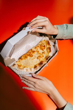 Golden Cheburek in Takeout Box on Vibrant Red