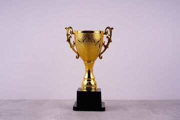Motivational and inspirational concept about progress and achievement. A golden trophy on white coloured background.