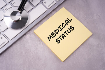 Medical and healthcare concept. MEDICAL STATUS written on a notepad. With background of stethoscope and keyboard.