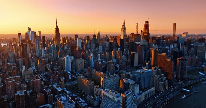 Splendid skyscrapers lit with orange light of setting sun. Metropolis panorama from drone footage.