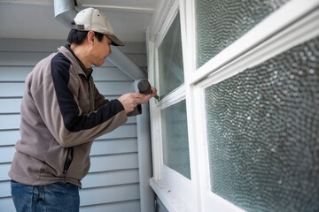 Worker removing old window putty using a hammer and chisel. Home maintenance project. - 792617323