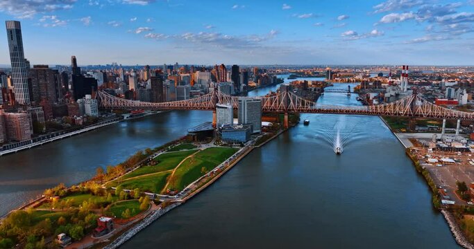 A boat passes under the Queensboro Bridge by the East River. Spectacular view on New York from drone at sunset.
