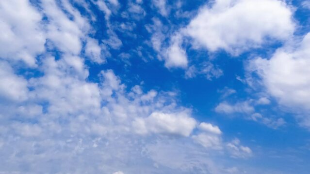 Floating white and grey clouds in the atmosphere. Changing cloudscape in the blue sky from low angle view. Timelapse.