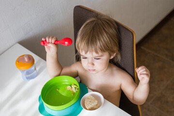 Adorable young child enjoying a nutritious breakfast in a cozy home setting, sitting in a high chair - 792623938