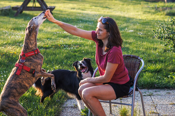 Woman playing with her dogs outdoors at backyard. Animal obedience training with pet treat or dog biscuit