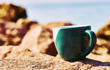 Relax, rest. Green ceramic cups, coffee tea beverages on a stone rocky sea bay 